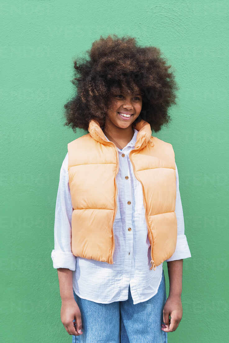 737x1106  Счастливая девушка в куртке, стоящей на зеленом фоне stock photo