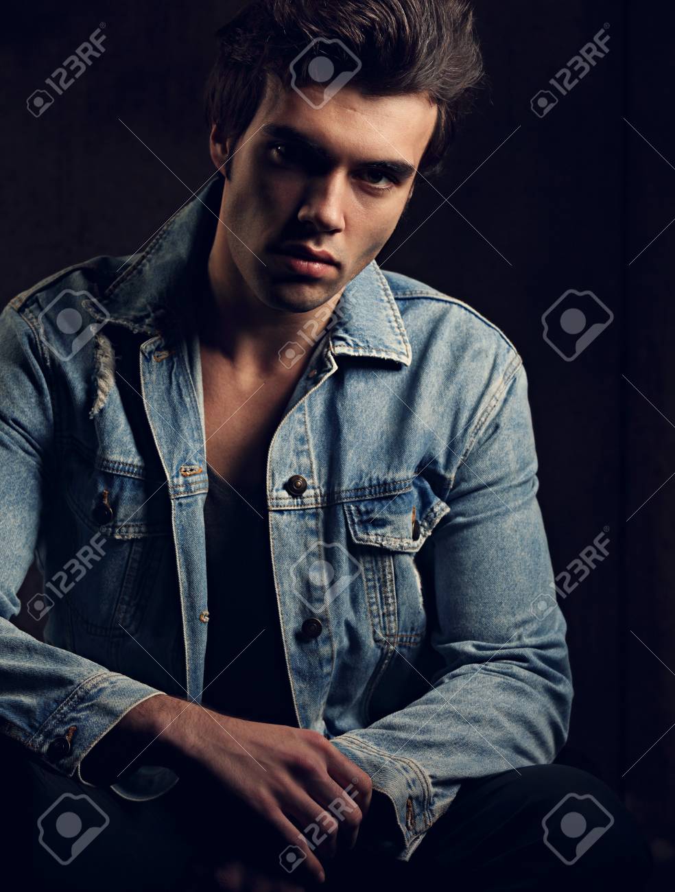 984x1300  Красивая мужская модель, позирующая в модных синих джинсовых куртке, смотря на темную тень. Крупным планом портрет Stock Photo, Picture и REALITCY FREE. Изображение 90928402.