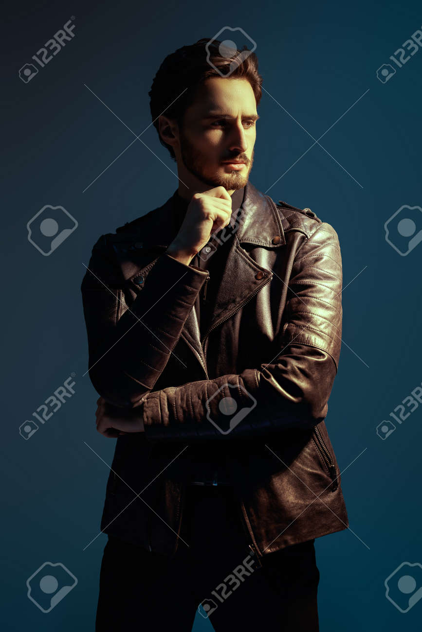 867x1300  Мужская красота, мода. Красивый жестокий мужчина из Брюне в кожаной куртке позирует на темно -синем фоне. Сток -фото, картинки и роялти. Изображение 185005003.