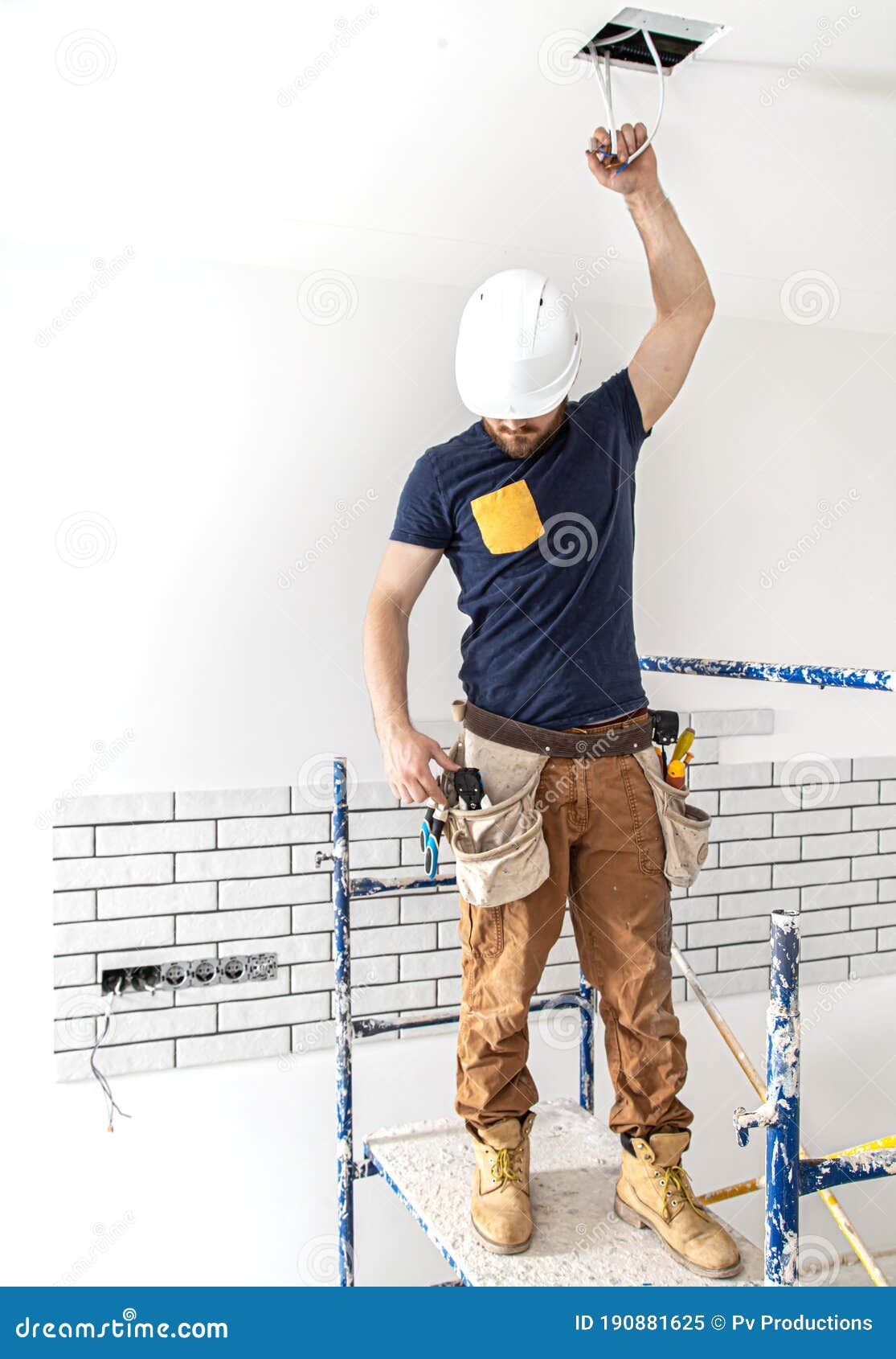 1115x1690  Электрик Строитель на работе, установка ламп на высоте. Профессионал в комбинезоне с электрическим инструментом изображение - изображение дома, электрическое: 190881625