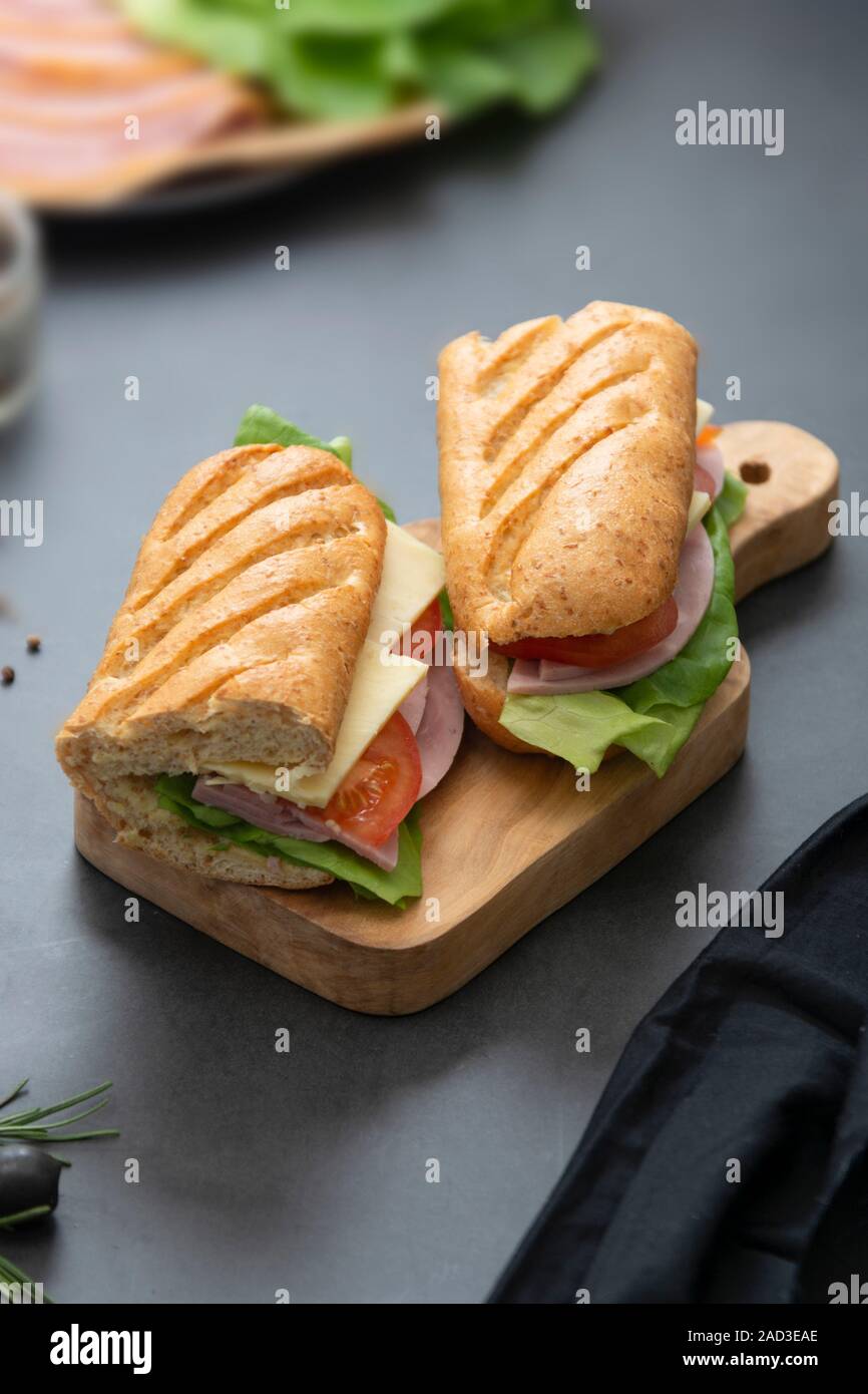 866x1390  Сэндвич с багейтом хлебом, ветчиной, салатом, томатом на темном фоне. Завтрак или фаст -фуд Stock Photo - Alamy