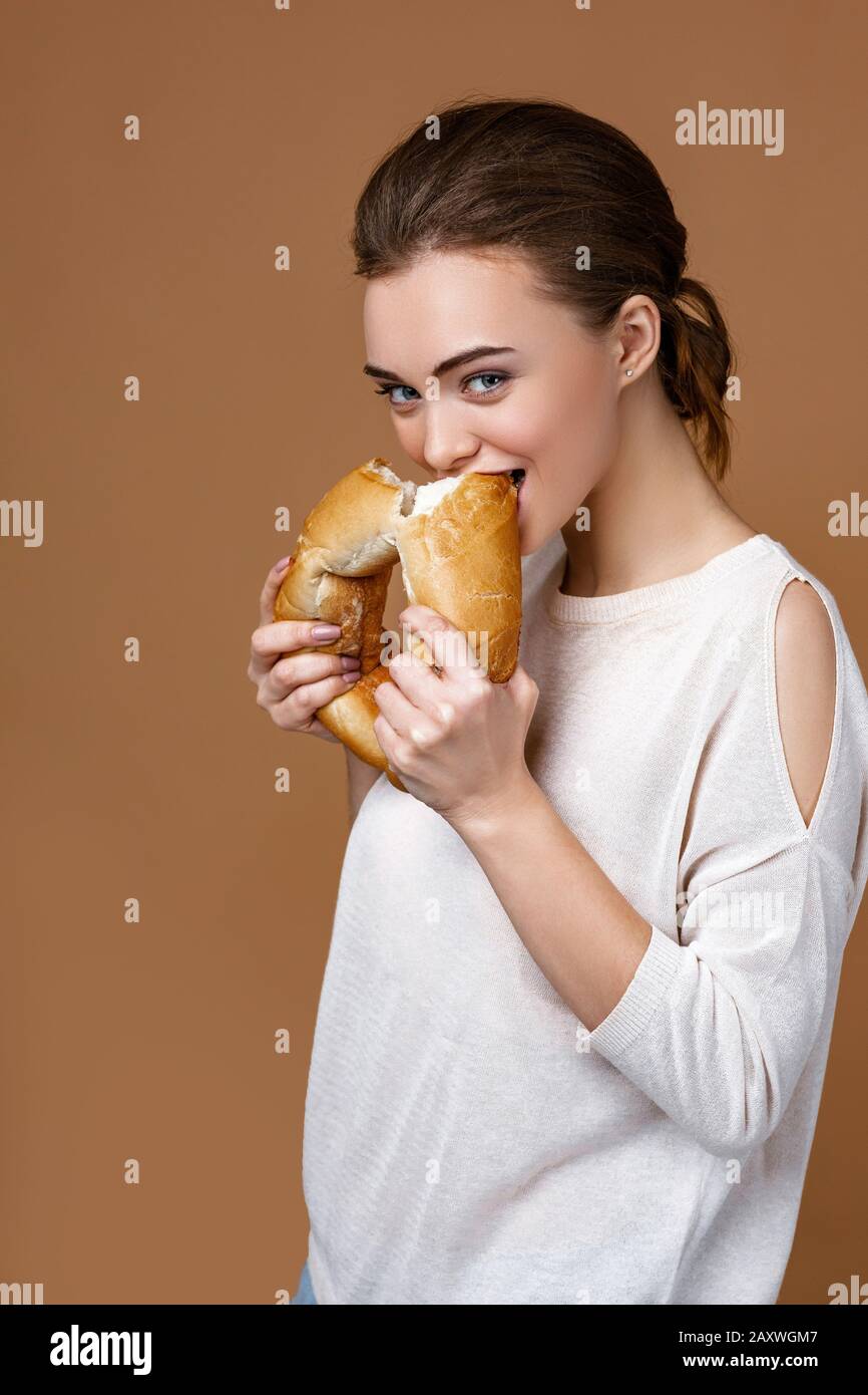 866x1390  Портрет красивой молодой женщины, ест вкусного хлебного багета на студийном желтом фоне. Девушка со свежим ароматным длинным хлебом stock photo - alamy