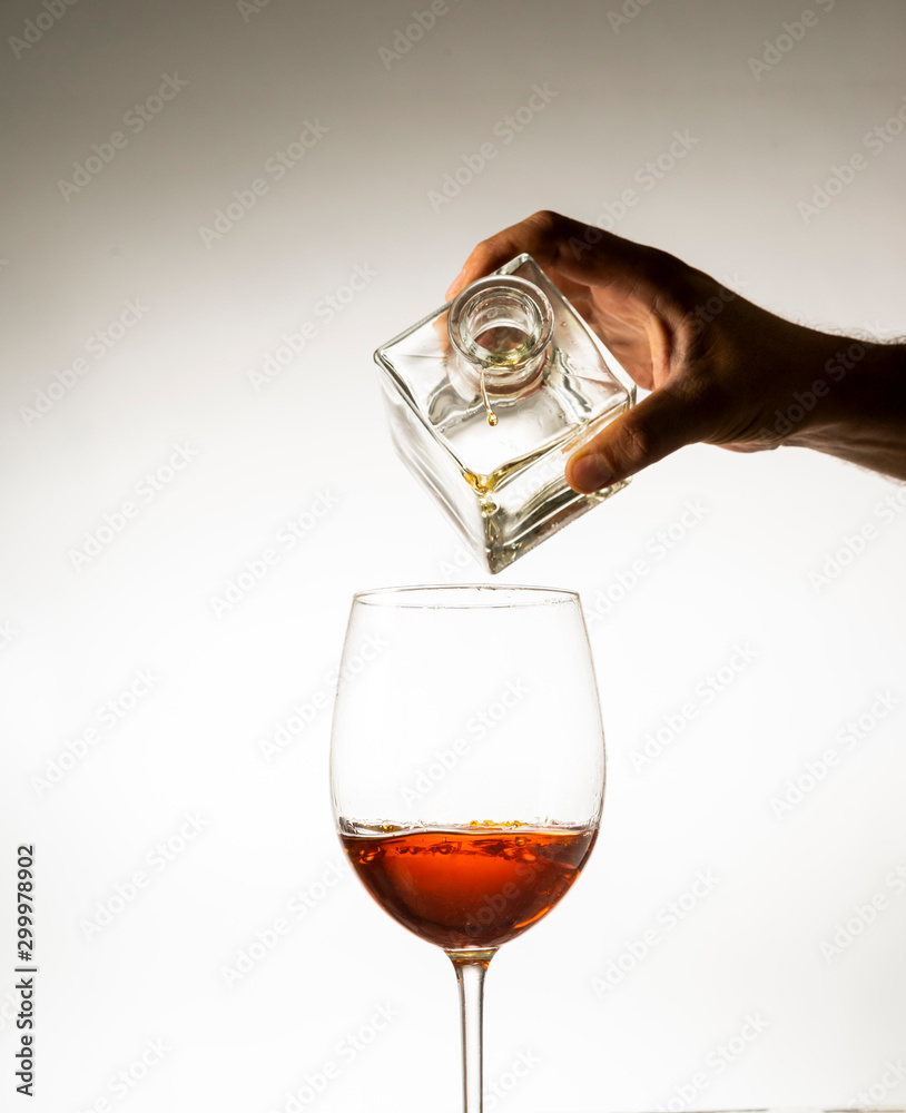 814x1000  Рука, заливая коньяк в стакан на легком фоне запаса, | Adobe Stock