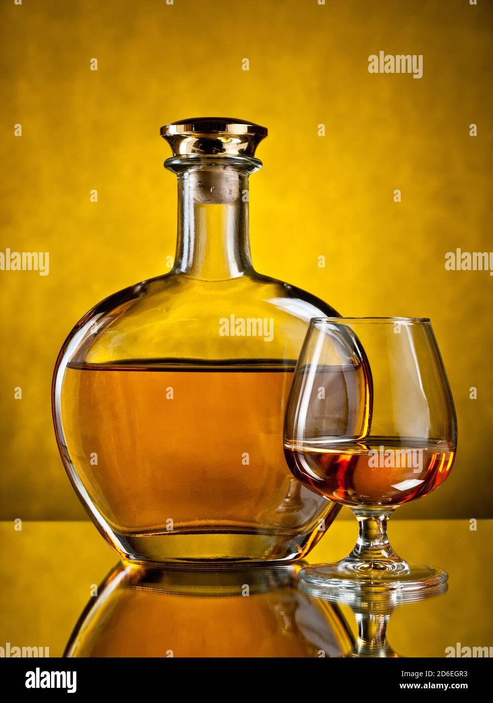 975x1390  Круглая элегантная бутылка коньяка с заполненным стеклом на желтом фоне Stock Photo - Alamy