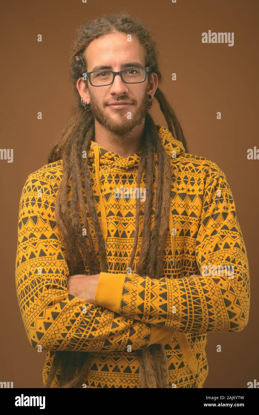 867x1390  Студийный снимок молодого красивого латиноамериканского мужчины с дредами в толстовке с коричневым фоном Stock Photo - Alamy