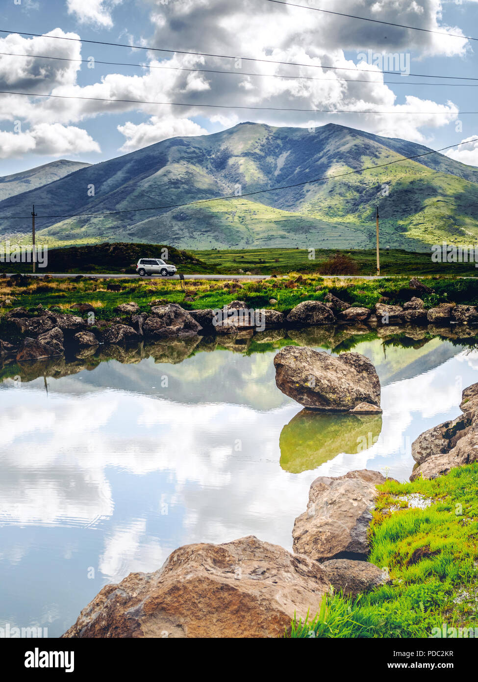 975x1390  Живописный снимок пруда и машины, проходящего мимо холмов на фоне, Армения Сток -Фото - Алами