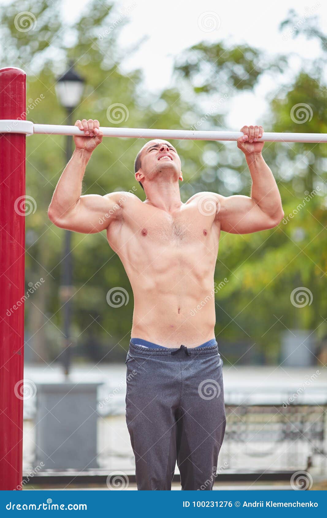 1067x1690  Молодой сильный человек делает подтягивание на горизонтальном баре на спортивной площадке летом в городе. Сток -фото - изображение взрослого, спортивное: 100231276