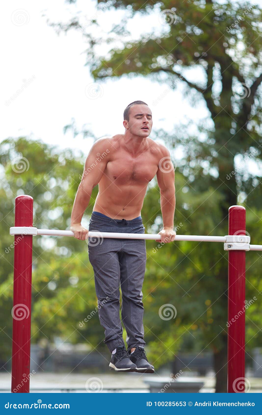 1067x1690  Красивый мускулистый мужчина делает подтягивания на горизонтальных стержнях на фоне парка. Концепция уличного спорта. Стоковое изображение - изображение снаружи, люди: 100285653