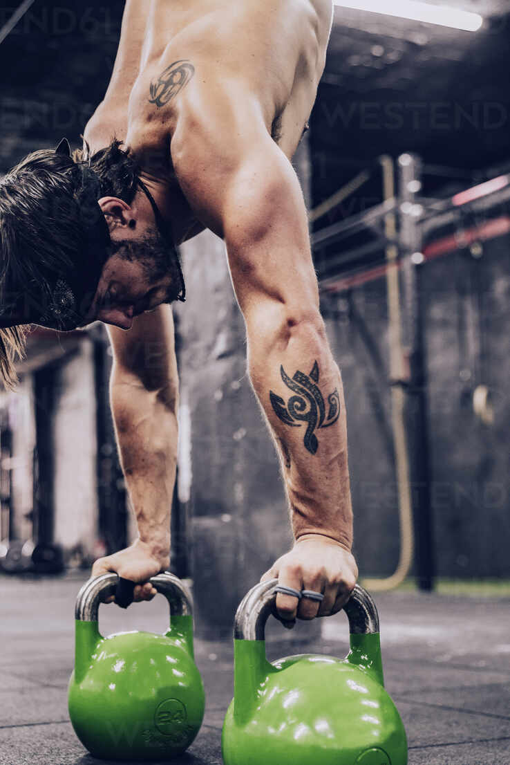 738x1106  Мускулистый человек в шортах, стоящих на руках с гантелями в современном спортзале на размыто