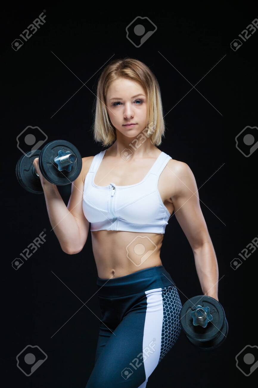 866x1300  Крупным планом портрет фитнес-мускулистой молодой девушки, позирующей с гантелями в тренажерном зале, изолированных на черном фоне. Изображение 140951282.