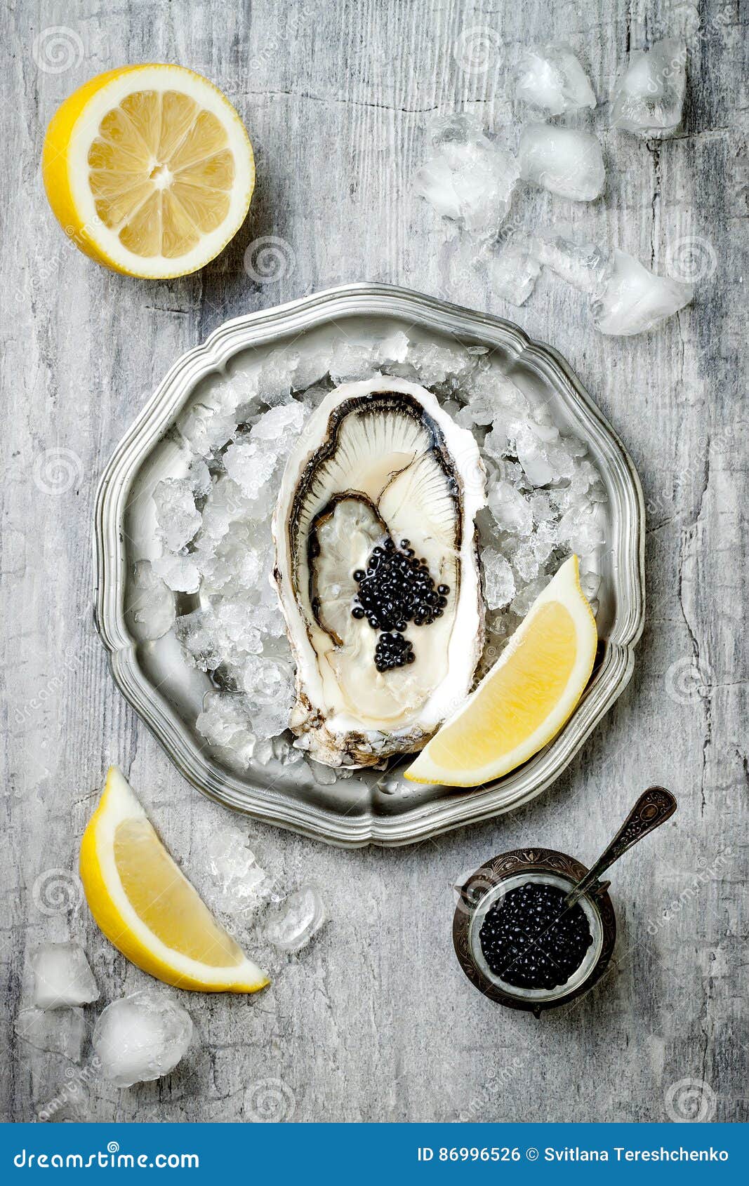 1067x1690  Открыта устрица с черной осетровой икрой и лимоном на льду в металлической пластине на сером бетонном фоне. Вид на верхнюю часть, плоское фото стоковое фото - изображение устриц, еда: 86996526