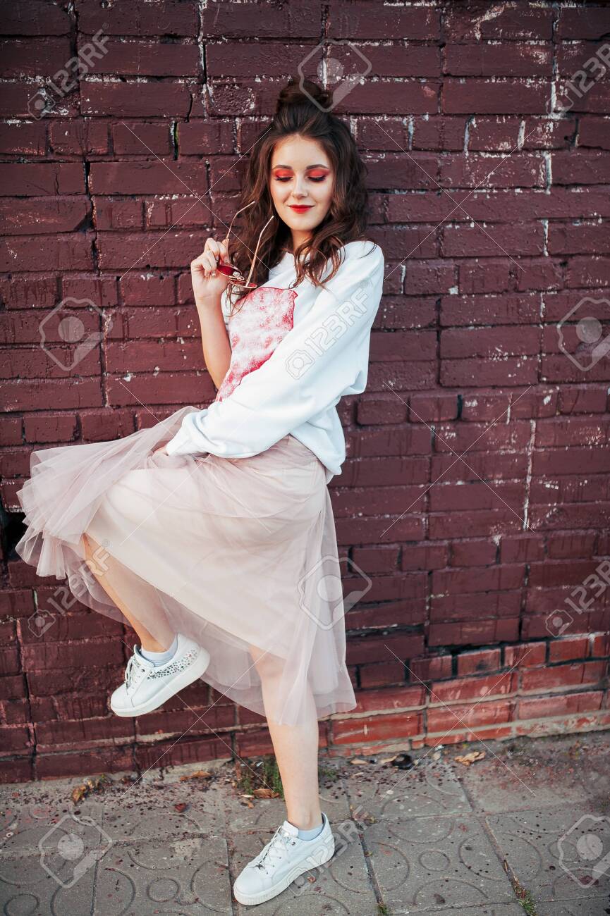 865x1300  Красивая стильная девушка в юбке на фоне кирпичной стены Stock Photo, Picture и Free Lavelty. Изображение 130043548.