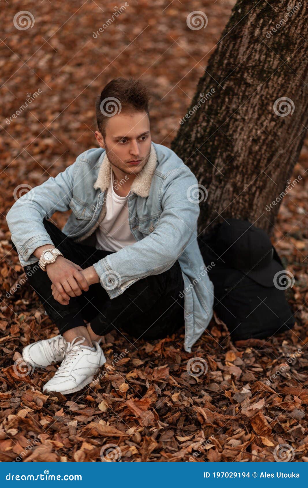 1067x1690  Модный крутой молодой человек в стильном жакетке джинсовой ткани в модных  военных в белых штанах тапках с рюкзаком, лежит возле де Стоковое Фото -  изображение насчитывающей рюкзак, джинсыы: 197029194