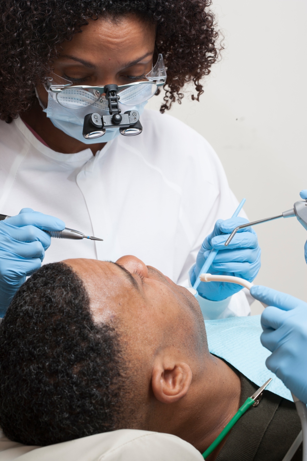 1000x1500  premium Photo | Улыбающийся молодой человек, сидящий в кресле стоматолога, пока доктор осматривает свои зубы 