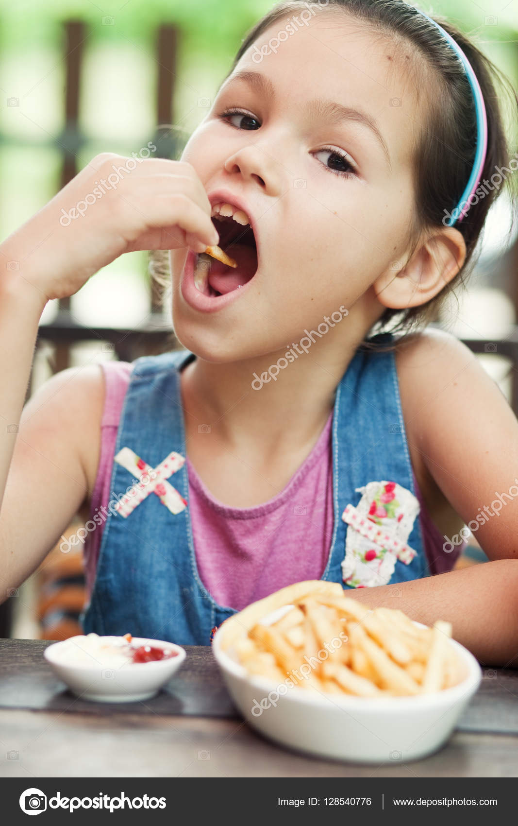 1067x1700  Маленькая девочка, которая ест картофель фри Стоковое фото © Radarani 128540776